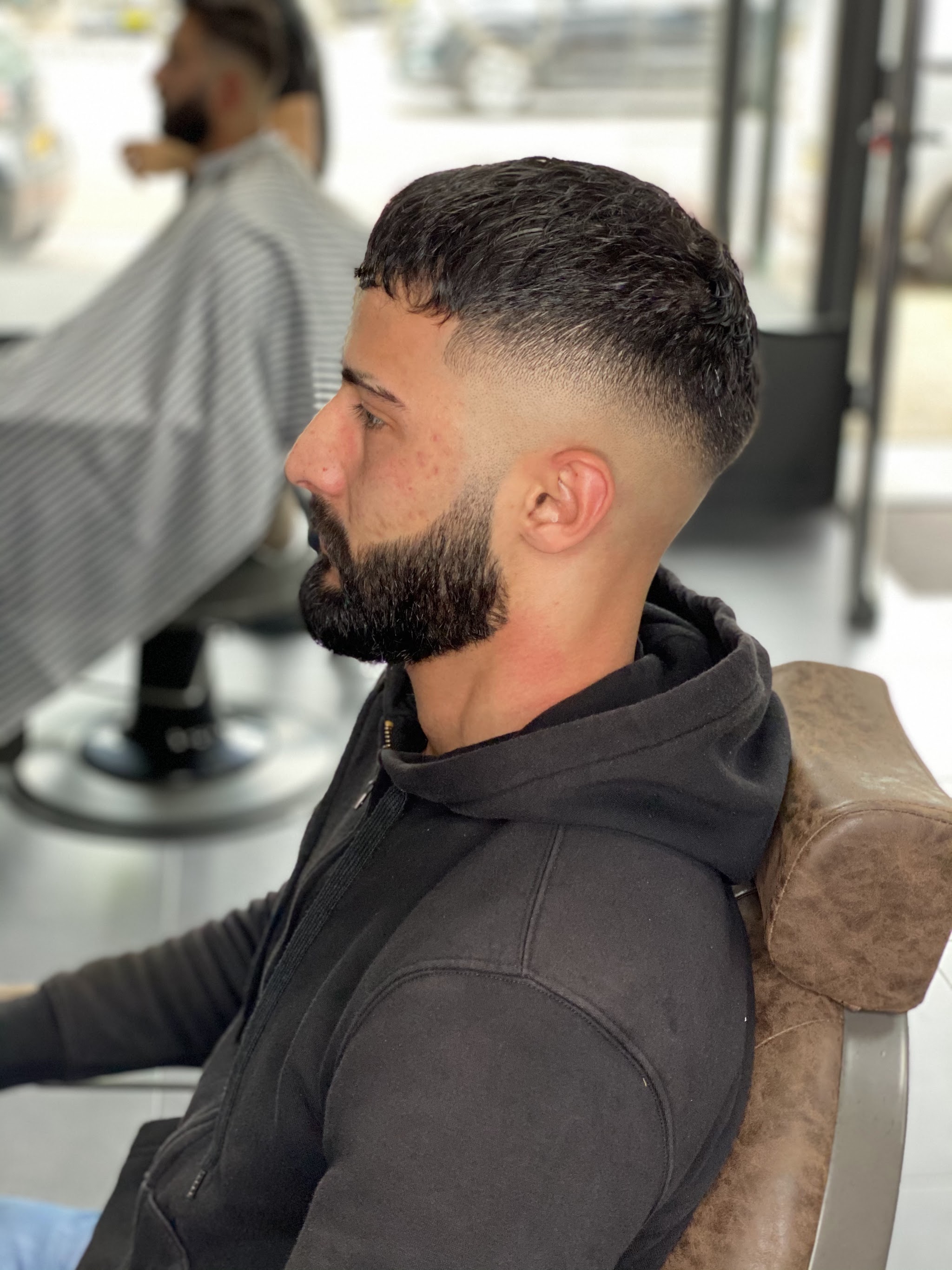 Klant met een fade en een volle, strak opgelijnde baard, van opzij